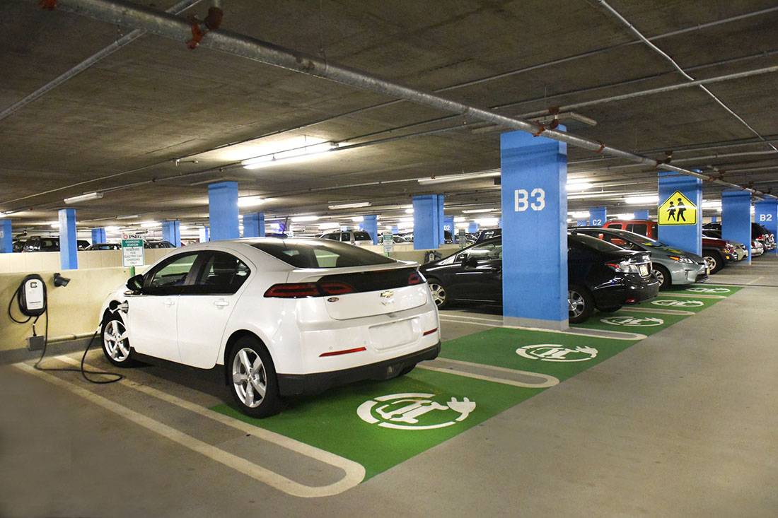 A photo shows several electric vehicles parked in a parking garage.